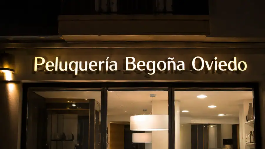 Letras corpóreas con iluminación frontal en la fachada de una peluquería