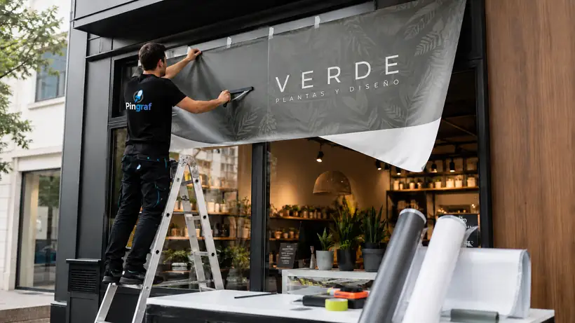 Instalador de Pingraf colocando vinilo impreso en el escaparate de una tienda